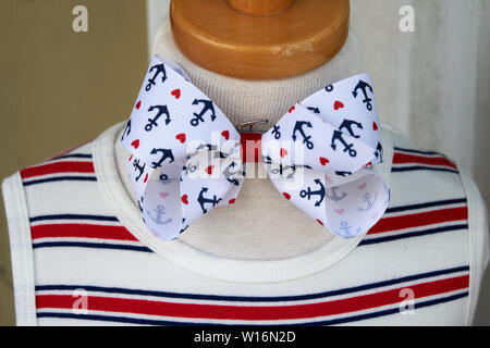 nautical childrens manequin display with red white and blue striped shirt and bow tied at the neck with red hearts and navy anchors on white grosgrain Stock Photo