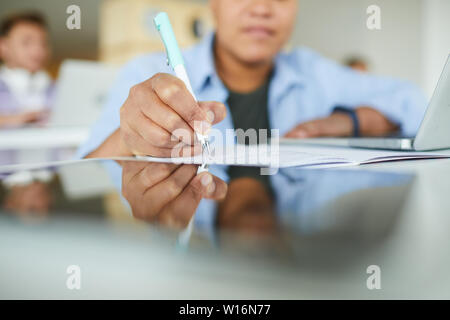 Close-up of busy Black woman sitting at table and making notes in workbook while working with information in library Stock Photo