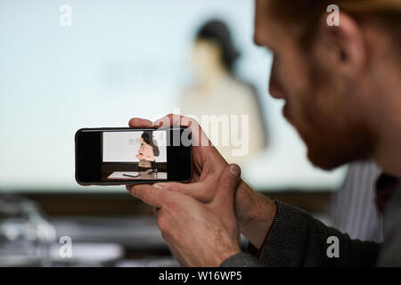 Close-up of man using smartphone while photographing Chinese speaker at conference, copy space Stock Photo