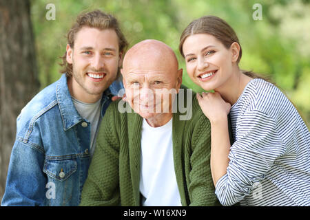 Relatives with elderly man walking in park Stock Photo
