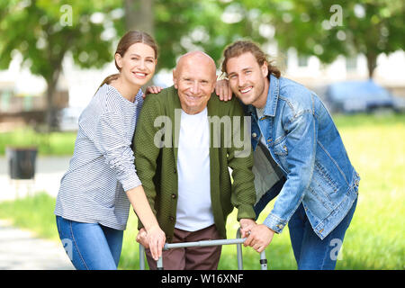 Relatives with elderly man walking in park Stock Photo