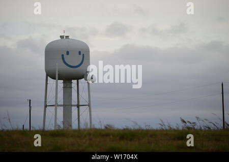 Happy, smiley face water tower in field on a cloudy day. Stock Photo