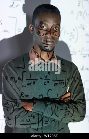 Portrait of content confident young African-American math teacher in black sweater standing against projection screen in conference room Stock Photo