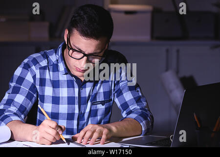 Busy young man working at home late in evening Stock Photo