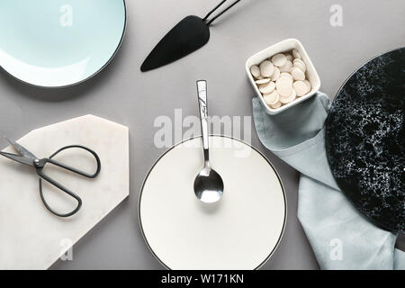 Different tableware and kitchen utensils on grey background Stock Photo