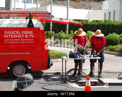 Local Bermuda utility workers in straw hats repairing fiber optic cable in Hamilton, Bermuda. Stock Photo