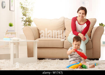 Mother and cute baby boy playing with toys at home Stock Photo