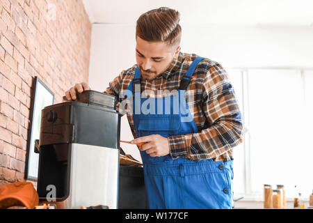 Man repairing coffee machine in kitchen Stock Photo