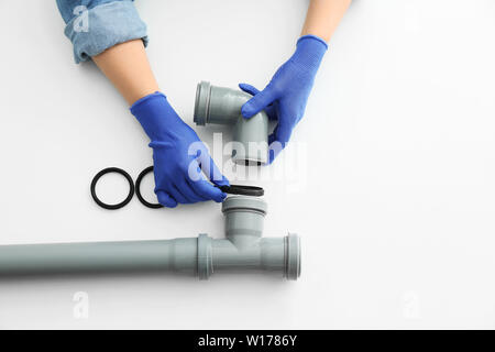 Plumber working with drain pipe on white background Stock Photo