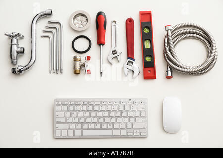 Computer keyboard and plumbing items on white background Stock Photo