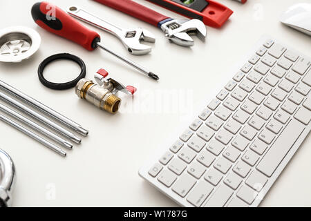 Computer keyboard and plumbing items on white background Stock Photo