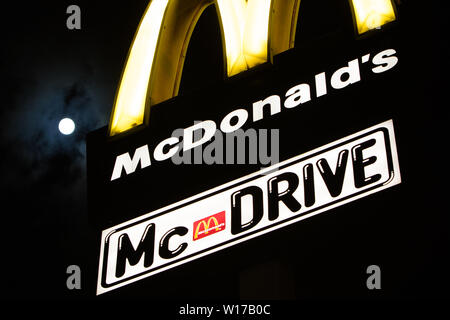 Lodz, Poland, Jan 2018 yellow McDonald's sign, night, clouds, moon in background, McDonald's restaurant fast-food chain logo, McDrive banner Stock Photo