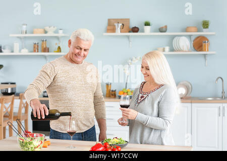 Happy mature couple drinking wine in kitchen Stock Photo