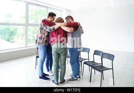 Young people hugging together at group therapy session Stock Photo