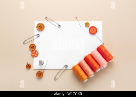 Set of sewing threads with accessories and sheet of paper on color background Stock Photo