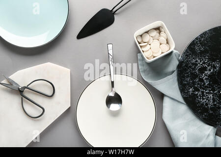Different tableware and kitchen utensils on grey background Stock Photo