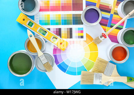 Cans of paints with brushes and palette samples on color background Stock Photo