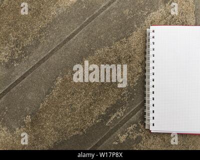 Notebook page on on asphalt concrete floor with copy space. Blank open notepad sheet on old cement floors background. view of open note book on gray o Stock Photo