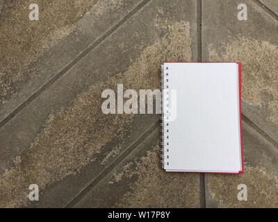 Notebook page on on asphalt concrete floor with copy space. Blank open notepad sheet on old cement floors background. view of open note book on gray o Stock Photo