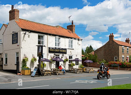 Motorbike passing the Grey Horse pub in Elvington, North Yorkshire, England UK Stock Photo