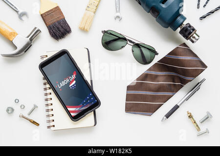 Table top view of decoration the sign of USA labor day background concept. Flat lay cell Smart Phone With Happy Labor Day USA Holiday and essential to Stock Photo