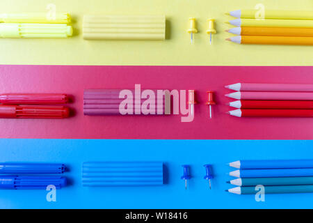 School concept with colored pencils, plasticine and office supplies on blue, red and yellow background. Flat lay, top view, copy space. Stock Photo