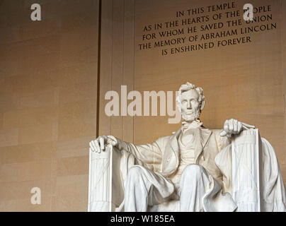 Large seated sculpture of Abraham Lincoln and the inscriptions of a quote of the Gettysburg Address speech on the wall inside the Lincoln Memorial in Stock Photo