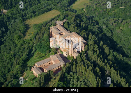 AERIAL VIEW. Secluded abbey in a setting of wooded hills. Monte Oliveto Maggiore abbey, Asciano, Province of Siena, Tuscany, Italy. Stock Photo