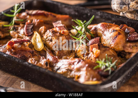 Portioned baked rabbit in a pan with onion rosemary and sauce Stock Photo