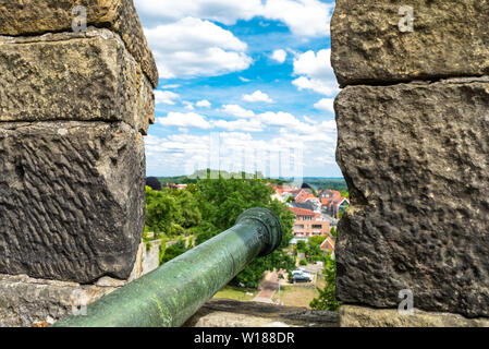 An antique cannon in red-yellow color on the walls of a medieval castle. Stock Photo
