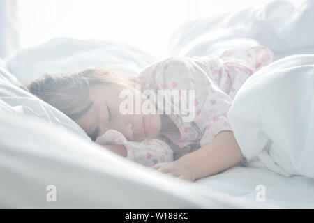 Asian little girl sleeping in the bed on the morning time with sunrise light soft focus sweet dream concept