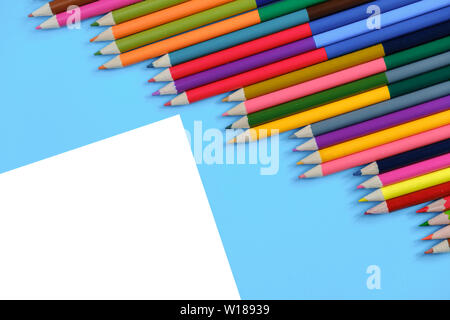 Creative flat lay back to school concept with colored pencils on blue and white background. Minimal concept art. Top view, copy space. Stock Photo