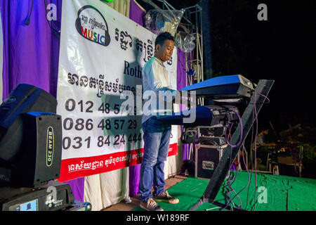 A Cambodian man is playing a keyboard on a small stage at a traditional Khmer wedding in Siem Reap, Cambodia. Stock Photo