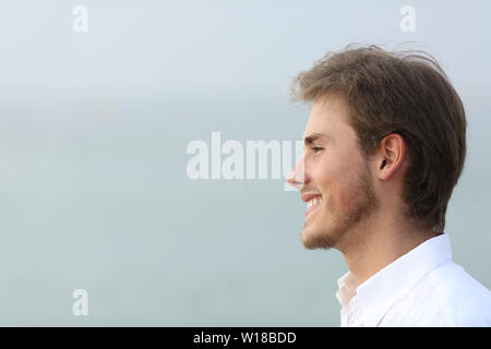 Side view portrait of a happy man looking away on the beach Stock Photo