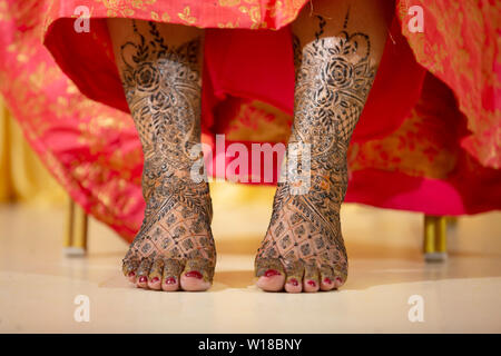 Henna on bride's feet on her wedding date Stock Photo