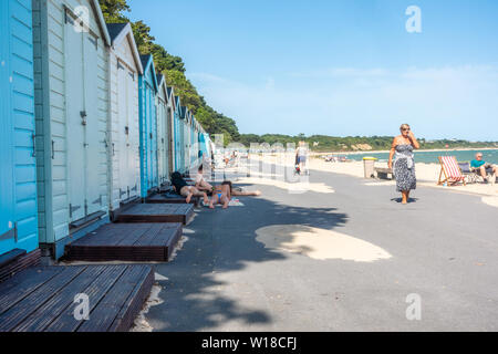 Row of beach huts in different pastel blue shades run along the top of Avon Beach at Mudeford, Christchurch in Dorset, UK. A sandy beach with pebbles. Stock Photo