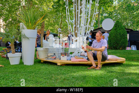Zagreb, Croatia, July 1, 2019.  Lumen Station installation in Park. Man reading a book sitting in outdoor reading room Stock Photo