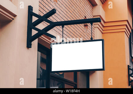 Empty signage and blank mock up hanging on street with copy space Stock Photo