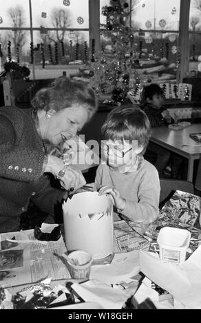 Prime Minister Margaret Thatcher shows Christopher Maddock, 5, how to turn a piece of cardboard into a crown, during her visit to Tudor Primary School in Finchley. Stock Photo
