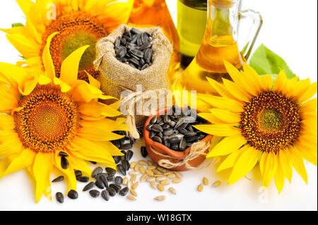 Yellow sunflowers with bottles of oil and a small bag of seeds on a white background Stock Photo