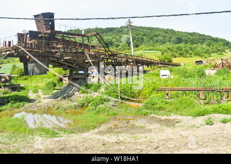 Rusty huge machines in abandoned coal mine. Heavy industry decay in Romania. Stock Photo