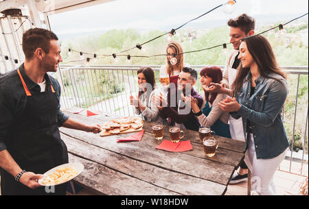 Happy group of friends drinking beer and eating pizza at brewery bar restaurant. concept with young people having genuine fun Stock Photo