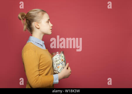 Teen girl with  jar full of money cash. Students fees, responsibility and saving money concept Stock Photo