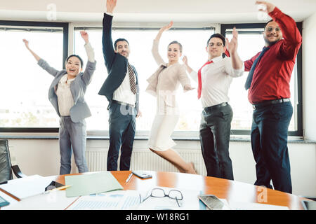 Diversity team of business people jumping high in the office  Stock Photo