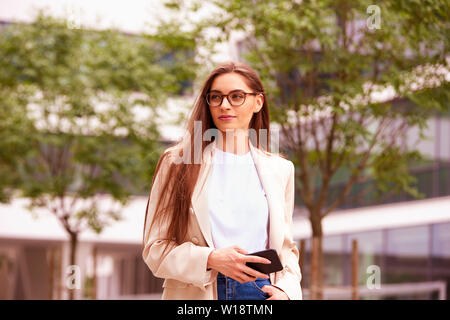 Shot of businesswoman using a phone while walking on the street. Stock Photo