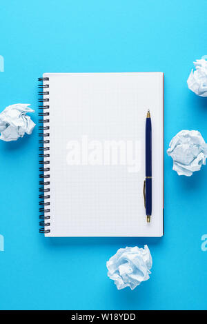 Open empty notebook, pen and crumpled paper balls on blue background. Creation process or creative attempts concept. Copy space. Stock Photo