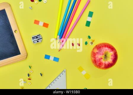 top view on suplies of school and red apple  on yellow background Stock Photo