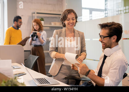 Cheerful confident team of brokers viewing papers while analyzing sales together in office, copy space Stock Photo