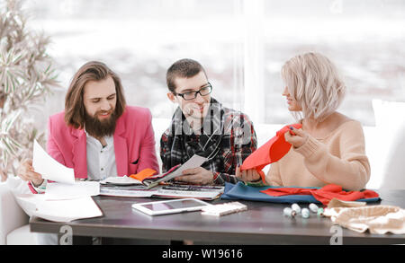 Smiling tailor businesswoman sitting at sewing machine Stock Photo