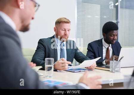 Group of young multicultural co-workers getting ready with reports before conference Stock Photo